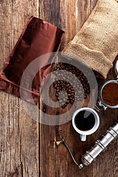 Bag of coffee on a wooden table. Coffee beans ground in a jar. Manual coffee grinder. Top view, place for text. Brown background.