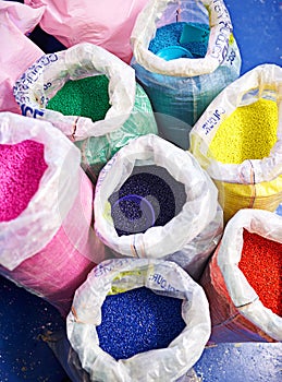 Bag, color and plastic resin with recycling for dye, manufacturing or ecology on floor in factory. PVC pellets, industry