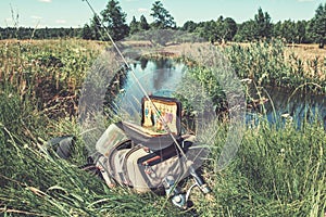 Bag with fishing essentials at riverside on sunny day