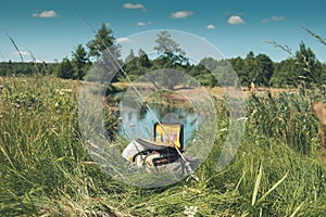 Bag with fishing essentials at riverside on sunny day