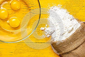 A bag of flour and broken chicken eggs in a glass bowl. Ingredients for the dough. Products for dough preparation.