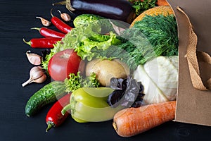 Bag of fresh vegetables on a black wooden table