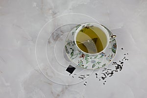 Bag of green tea with water in a porcelain cup