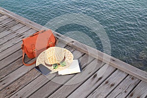 Bag,hat, sunglass and telephone in wood bridge on the beach