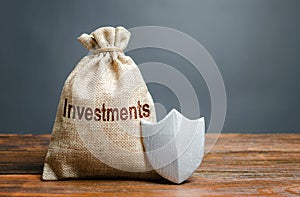 Bag with the inscription investment and shield. Guarantee of protection of foreign investment in the economy