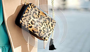 Bag in leopard print close-up. large shopping leather handbag in female hands. Woman walking in the city. Girl in a beige coat