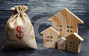 Bag with money and dollar sign and wooden houses. Financing in the country. Investing money in real estate. Saving and