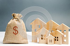 Bag with money and dollar sign and wooden houses. Financing in the country. Investing money in real estate. Saving and