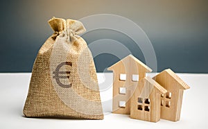 Bag with money and euro sign and wooden houses. Financing in the country. Investing money in real estate. Saving and accumulation