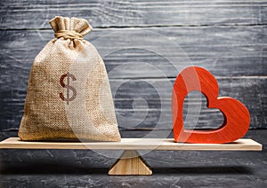 Bag with money and red wooden heart on the scales. Money versus love concept. Passion versus profit. Family or career choice.