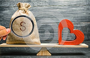 Bag with money and red wooden heart on the scales. Money versus love concept. Passion versus profit. Family or career choice.