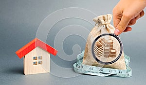 Bag with money and tape measure with a wooden house. The concept of a limited real estate budget. Low subsidies. Lack of
