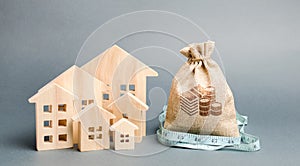 Bag with money and tape measure with a wooden houses. The concept of a limited real estate budget. Low subsidies. Lack of photo