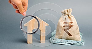 Bag with money and tape measure with a wooden houses. The concept of a limited real estate budget. Market crisis. Bankruptcy. Low