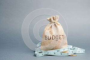 Bag with money and tape measure and the word budget. Limited budget. Lack of money. The concept of accumulating money in the