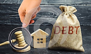 A bag of money with the word Debt, house and gavel. The concept of debt for housing. Mortgage. Real estate, loans market concept.