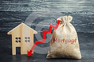 Bag with the money and the word Mortgage and arrow to down and house. Low interest in mortgages. Reducing interest payments for