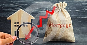 Bag with the money and the word Mortgage and arrow to down and house. Low interest in mortgages. Reducing interest payments for