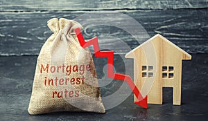 Bag with the money and the word Mortgage interest rates and arrow to down and house. Low interest in mortgages. Reducing interest photo