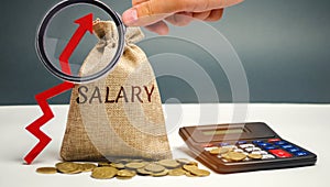 Bag with money and word Salary and up arrow with calculator. increase of salary, wage rates. promotion, career growth. raising the photo