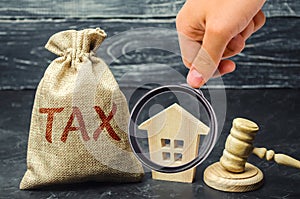 A bag with money and the word tax next to a wooden house. Taxes on real estate, payment. Penalty, arrears. Register of taxpayers