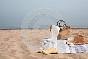 Bag and other beach items on sandy seashore, space for text