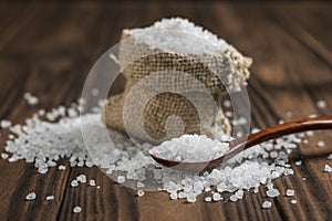 A bag of salt and a wooden spoon on a rustic table.
