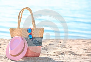 Bag, sunglasses and hat on sand near sea