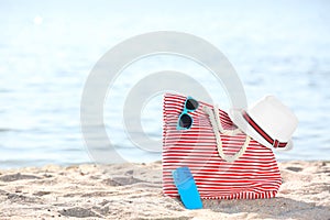 Bag, sunglasses and hat on sand near sea. Beach object