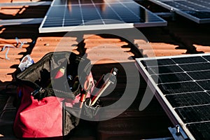Bag of technician tools and solar panel on roof during sunrise.Renewable energies and green energy concept