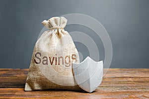 Bag with the words Savings and protection shield. Concept of protection of savings and cash, guaranteed deposits.