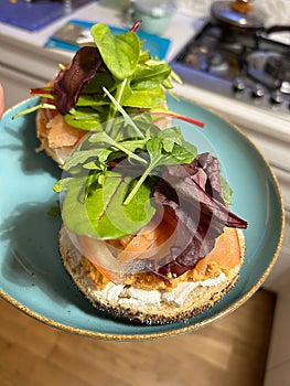 bagel with cheese and salmon, spinach and beetroot leaves, classic salmon sandwich, colorful sandwich on a plate