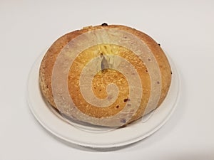 Bagel with cheese on small white plate on white background
