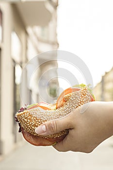 Bagel cut in half. Girl holding in her hands