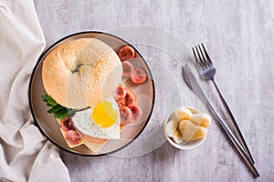 Bagel with heart-shaped boiled egg, tomato, cheese and herbs on a plate. Top view