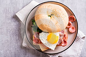 Bagel with heart-shaped boiled egg, tomato, cheese and herbs on a plate. Top view. Closeup