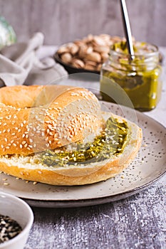 Bagel with pistachio cream butter for breakfast on a plate on the table vertical view