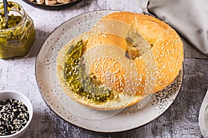 Bagel with pistachio cream butter and a jar of butter on a plate on the table