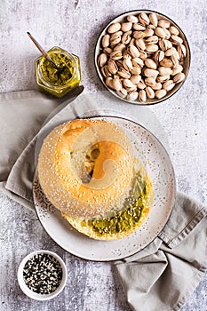 Bagel with pistachio cream butter and a jar of butter on a plate on the table top and vertical view