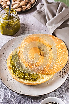 Bagel with pistachio cream butter and a jar of butter on a plate on the table vertical view