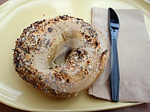 Bagel and Plastic Knife on a yellow plate