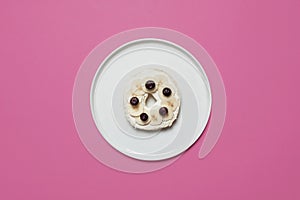 Bagel on a plate on a pink background