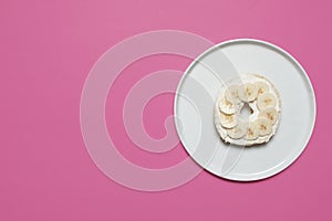 Bagel on a plate on a pink background