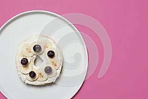 Bagel on a plate on a pink background
