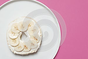 Bagel on a plate on a pink background