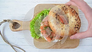 Bagel with salmon and cream cheese with hand