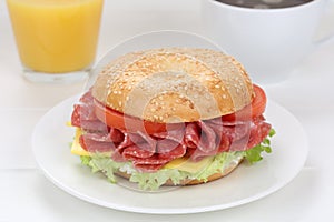 Bagel sandwich for breakfast with salami ham, orange juice and c