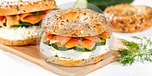 Bagel sandwich with salmon and cream cheese for breakfast on a kitchen board panorama