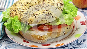 Bagel sandwich with salmon and raw vegetables on a plate