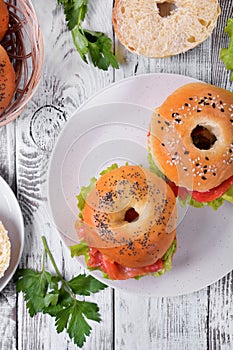 Bagel sandwich with smoked salmon and lettuce salad on ceramic plate